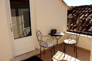 a balcony with chairs and a table and a wine rack at Guest House Dijana in Korčula