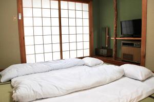 two pillows on a bed in a room with a window at Beppu Kannawa Onsen HIROMIYA in Beppu