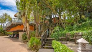 Casa con terraza de madera con bancos y árboles en Pousada Boulevard Bombinhas, en Bombinhas