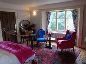 a bedroom with a bed and two chairs and a table and a window at Redlynch Lodge in Redlynch