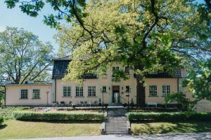 uma casa grande com uma árvore em frente em Balingsholm em Huddinge