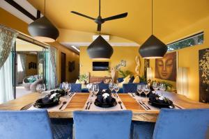a dining room with a long wooden table and blue chairs at Baan Putahracsa in Laem Sor