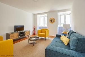 ein Wohnzimmer mit einem blauen Sofa und gelben Stühlen in der Unterkunft Bica Apartment in Lissabon