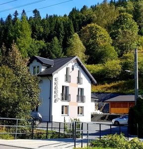 a white house with a black roof at Dom Goscinny Skarpa in Krynica Zdrój