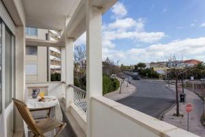 einen Balkon mit einem Tisch und Straßenblick in der Unterkunft Carcavelos - Holiday Beach Apartment in Carcavelos