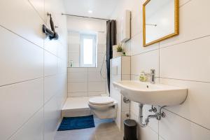 a white bathroom with a sink and a toilet at Adora Apartment Hilden in Hilden