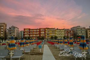 een rij strandstoelen en parasols op een strand bij Hotel Resort Marinella in Gabicce Mare