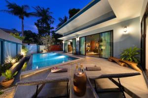 a backyard with a swimming pool and a house at Villa Baan Suaan Kluay Mai in Laem Sor