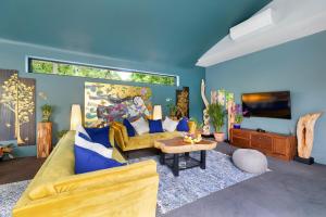 a living room with a yellow couch and blue walls at Villa Baan Suaan Kluay Mai in Laem Sor