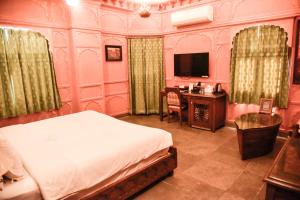 a bedroom with a bed and a desk and a television at Pearl Palace Heritage Boutique Hotel in Jaipur