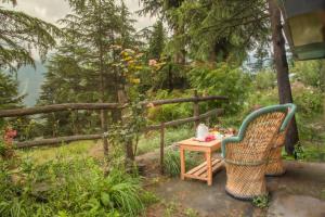 a chair and a table in a garden at The Monk Campsite by Livingstone in Kalpa