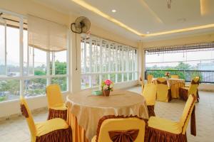 RedDoorz Plus @ Hotel Sempurna Watervang Lubuk Linggau في Lubuklinggau: غرفة طعام بها طاولات وكراسي ونوافذ صفراء
