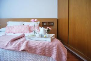 a bedroom with a bed with pink sheets and a tray with flowers on it at Encantadora Casa cerca del mar con piscina SOLO FAMILIAS in Gandía