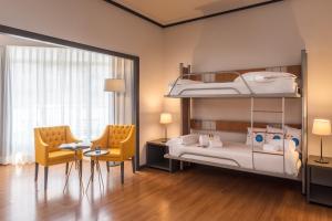 - une chambre avec des lits superposés, un bureau et deux chaises dans l'établissement Hotel Madrid Plaza de España, Affiliated by Meliá, à Madrid