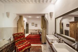 a bathroom with a tub and a chair and a sink at Le Farnatchi in Marrakesh
