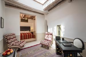 a living room with a table and chairs and a bed at Le Farnatchi in Marrakesh
