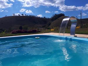 a swimming pool with a water fountain at Pousada Chalés dos Montes in Santana dos Montes