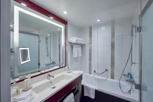 a bathroom with a large mirror and a sink and a shower at Disney Hotel New York - The Art of Marvel in Chessy
