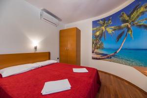 a bedroom with a red bed with a painting on the wall at Apartments Nada in Baška