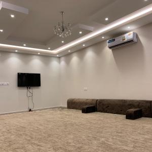 Habitación con sofá y TV en la pared. en Al Taif Villas, en Taif