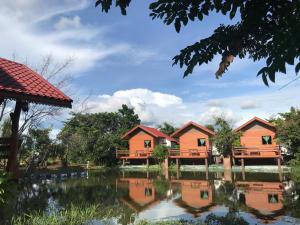 une rangée de cottages à côté d'un lac dans l'établissement Baan Suan Sukjai Resort, à Chaiyaphum