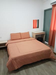 a bedroom with a bed with an orange bedspread at Sembulan @ Ning Guesthouse 宁舒民宿 in Kota Kinabalu
