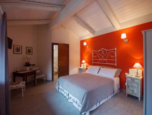 Un dormitorio con una pared de acento naranja y una cama en La Ida Bed and Breakfast, en Villareggia
