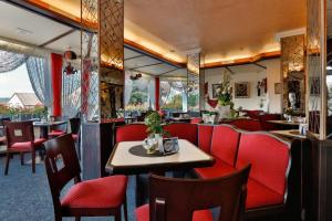 um restaurante com cabinas vermelhas, mesas e cadeiras em Themen Hotel Terrassen Cafe em Bad Münder am Deister