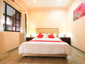 1 dormitorio con 1 cama grande con almohadas rojas en OYO 44084 Ombak Inn Chalet, en Pangkor