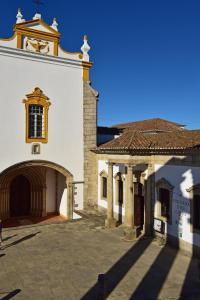 un grand bâtiment blanc avec une porte et une église dans l'établissement Pousada Convento de Evora, à Évora