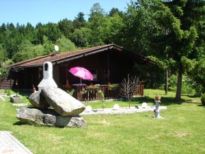 a house with a pink umbrella and a rock at Gerda's Ferienhäuser in Eppenschlag