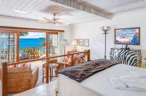 FriendshipにあるBequia Beach Hotel - Luxury Resortのベッドルーム1室(ベッド1台付)、海を望むバルコニーが備わります。