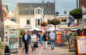 a group of people walking down a street at Carpe Diem Egmond aan Zee by Urban Home Stay in Egmond aan Zee