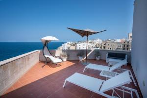 a balcony with white furniture and an umbrella at Covo dei Saraceni in Polignano a Mare
