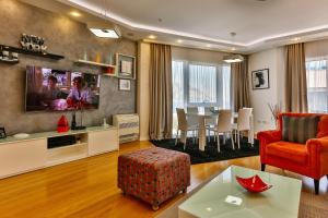 a living room with a red chair and a tv at DeLux and Urban apartments Hotel Tre Canne Budva in Budva