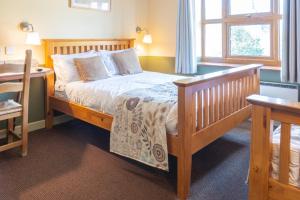 a bedroom with a wooden bed and a desk at The Half Moon Inn and Country lodge in Yeovil