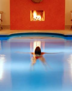 uma pessoa a nadar numa piscina em frente a uma lareira em Seehotel Am Neuklostersee em Neukloster