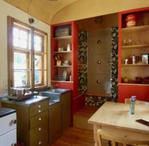 a kitchen with red walls and a sink and a table at Benno der Zirkuswagen in Tettau