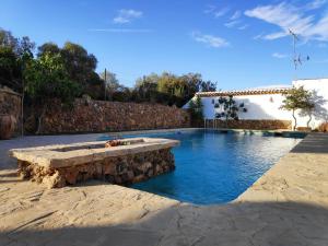 uma piscina com um banco de pedra em frente a uma casa em Cortijo El Arrejadero em Villanueva del Rosario