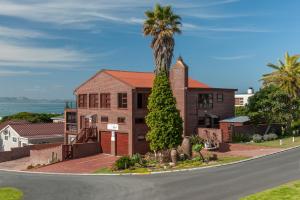 een huis met een palmboom voor een straat bij White Shark Guest House in Gansbaai