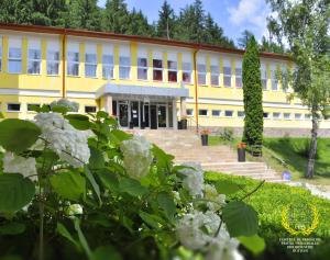 ein gelbes Gebäude mit weißen Blumen davor in der Unterkunft HOSTEL CPPI Vest in Buşteni