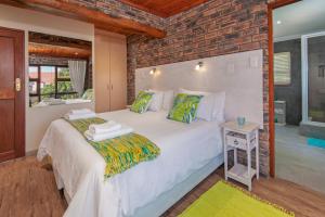 a bedroom with a white bed with a brick wall at White Shark Guest House in Gansbaai