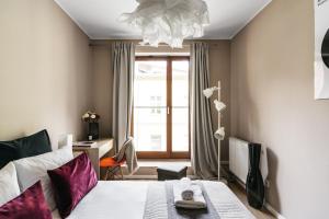 - une chambre avec un lit doté d'oreillers violets et d'une fenêtre dans l'établissement Harmonica Home by LoftAffair, à Cracovie