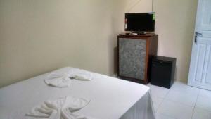 um quarto com uma cama e uma televisão numa mesa em Pousada Águas do Piruí em Arembepe