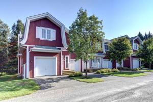 una casa roja con un garaje blanco en una calle en Borealis by Rendez-Vous Mont-Tremblant, en Mont-Tremblant