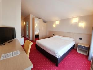 ein Hotelzimmer mit einem Bett und einem Flachbild-TV in der Unterkunft Hotel Ristorante al Giardinetto in Colle Umberto