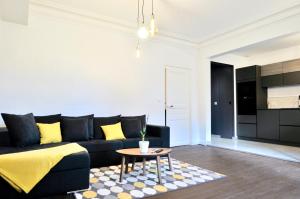 a living room with a black couch and a table at Appart Hotel NuitéeJour Le Mans Centre Jaurès in Le Mans