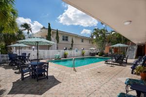 una piscina con sillas, mesas y sombrillas en Sea Garden by the Sea, en Fort Lauderdale