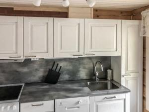 eine Küche mit weißen Schränken und einer Spüle in der Unterkunft Holiday Home Pajalan hirsitupa by Interhome in Kuusamo