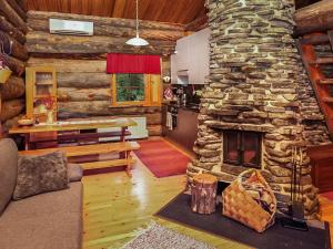 a living room with a stone fireplace in a log cabin at Holiday Home Luostonseita 3 by Interhome in Luosto